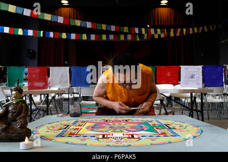 Monaco tibetano opere attentamente su un coloratissimo Mandala di sabbia. Foto Stock