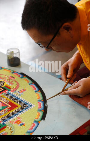Monaco tibetano opere attentamente su un coloratissimo Mandala di sabbia. Foto Stock
