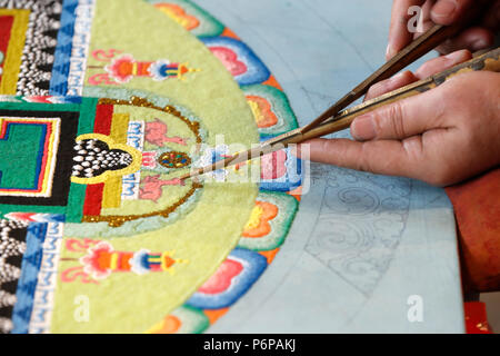 Monaco tibetano lavorando sulla sabbia mandala. Close-up. Foto Stock