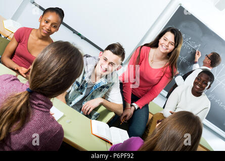 Bella giovani studenti di diverse nazionalità seduto e sorridente in aula mentre la rottura Foto Stock