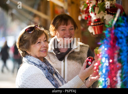 Attraenti donne mature camminando sul mercato di Natale e la scelta di gioielli. Focus sulla sinistra donna Foto Stock
