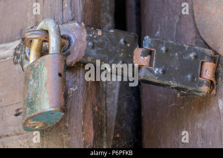 Chiusura del lucchetto e vecchio hasp su una vecchia porta di legno. Bloccata la vecchia porta con una ragnatela. Foto Stock