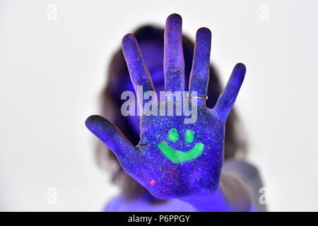 Auto-portraite con neon di make-up e luci UV per rendere la vernice glow. Arresto e sorriso. colorato creative ritratto di una giovane donna. Foto Stock