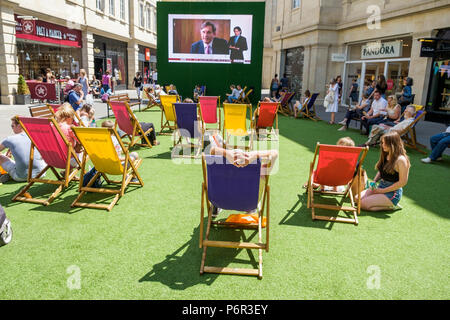 Bath, Regno Unito, 2 luglio, 2018. Come bagno gode di un altro molto calda e soleggiata giornata gli acquirenti sono ritratte godendo il sole in SouthGate shopping center dove un grande schermo è stato impostato in modo che gli appassionati di tennis possono guardare il torneo di Wimbledon Tennis Championship, forecasters prevedono che il clima caldo proseguirà anche nella prossima settimana. Foto Stock