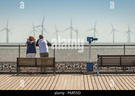 Skegness, Regno Unito. Il 2 luglio 2018. Turisti che si godono il caldo a Skegness Pier e visualizzando le turbine eoliche offshore attraverso il calore opacità sulla costa est verso il solitamente fredda del mare del Nord. Credito: Steven Booth/Alamy Live News. Foto Stock