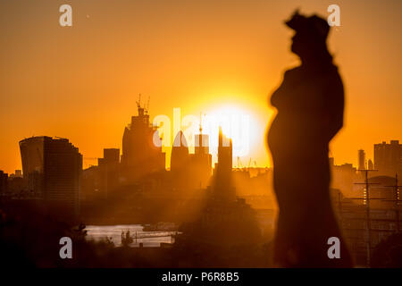 Londra, Regno Unito. 02 Luglio, 2018. Meteo REGNO UNITO: drammatico tramonto raggi rompere attraverso città edifici aziendali con un stagliano donna incinta a guardare il sole andare giù dalla parte superiore del parco di Greenwich la fine di uno dei giorni più caldi di estate finora. Credito: Guy Corbishley/Alamy Live News Foto Stock