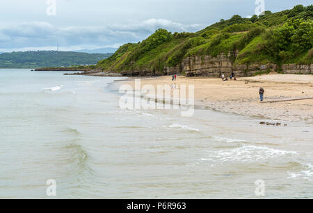 La gente camminare sulla spiaggia a Benllech sull'Isola di Anglesey Foto Stock