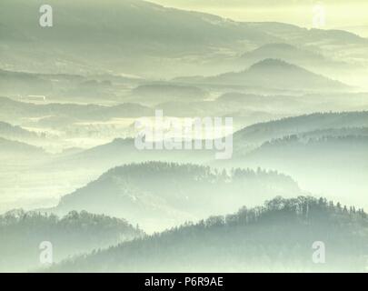 Nebbia dorata al di sopra di colline arrotondate nel paesaggio. Profilo del paesaggio reale in mattina luce dorata. Foto Stock