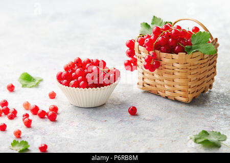 Coppa di cottura ed un piccolo cesto di vimini con ribes rossi freschi (ribes rubrum). Foto Stock