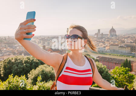 Giovane donna in posa tenendo selfie con lo smartphone in viaggio in Firenze, Toscana, Italia Foto Stock