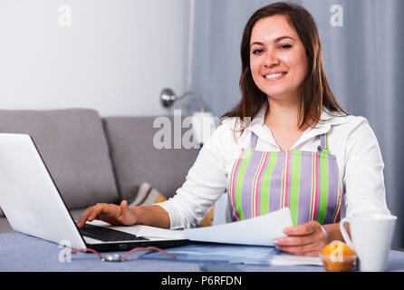 Giovane donna navigando attraverso utili suggerimenti per la cottura in Internet Foto Stock