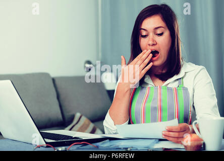 Giovane donna navigando attraverso utili suggerimenti per la cottura in Internet Foto Stock