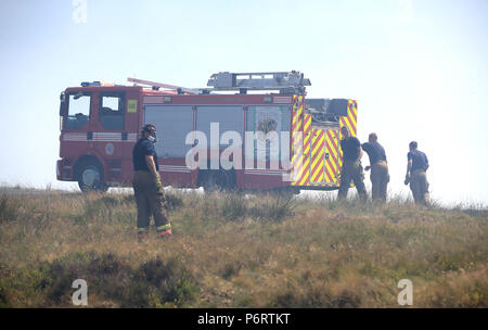 Un vigile del fuoco da Tyne and Wear Fire and Rescue Service mette fuori fuoco sulla collina di inverno vicino a Bolton, come più di 20 motori Fire sono in scena con equipaggio affrontare la brughiera di incendi. Foto Stock