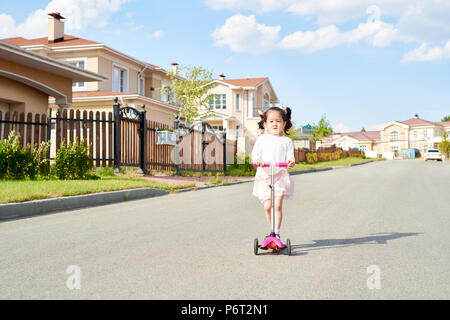 Poco ragazza asiatica Scooter di equitazione Foto Stock