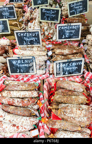 Selezione di salame, sul mercato in stallo. Noce, formaggio di capra, Camembert e boschi di castagno e indurito aromatizzato salsicce disposte in scatole con etichette di prezzo Foto Stock