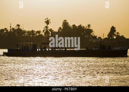 Silhouette di un tradizionale vecchio chiatta viaggiare in barca sul fiume Nilo attraverso il paesaggio rurale paesaggio al tramonto Foto Stock