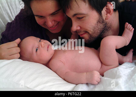 Sorridenti genitori guardando il loro bambino adoringly Foto Stock