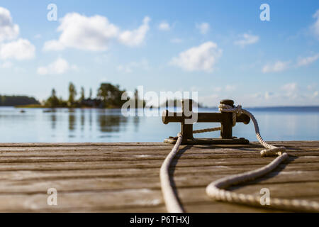 Ponte di Legno e placchetta con corda bianco legato attorno ad essa nella parte anteriore della soleggiata seascape Foto Stock