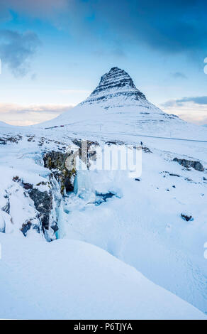 Penisola Snaefellsness, Western Islanda, l'Europa. Congelati Kirkjufellfoss cascata in inverno con Kirkjufell in montagna lo sfondo. Foto Stock