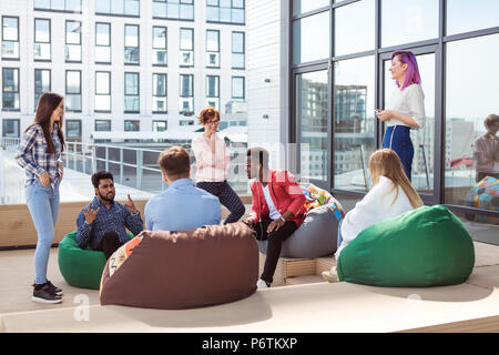 Business meeting di giovani talanted migliori fotografi. Vista superiore del team buiness brainstorming mentre è seduto in ufficio zona lounge Foto Stock
