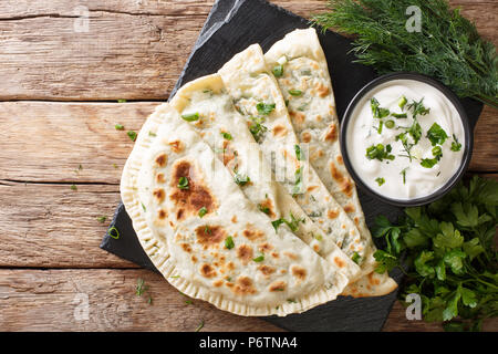 Azerbaijani cibo: flatbread qutab con verdi e yogurt vicino sul tavolo. parte superiore orizzontale vista da sopra Foto Stock