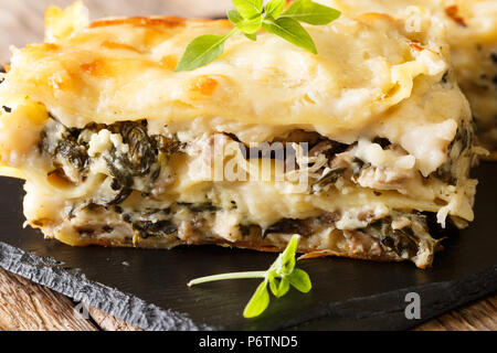 Lasagne in bianco con pollo e funghi di bosco, formaggio e salsa besciamella close-up su una piastra di ardesia orizzontale. Foto Stock