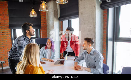 Varie gruppo multietnico di giovani imprenditori in office boardroom radunare intorno al tavolo bianco, discutendo la loro strategia commerciale e sh Foto Stock