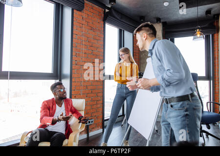 African American studente che chiede di spiegare qualche domanda sulla lavagna a fogli mobili durante la lezione con business coach, multirazziale equipaggio o avente il brainstorming sess Foto Stock