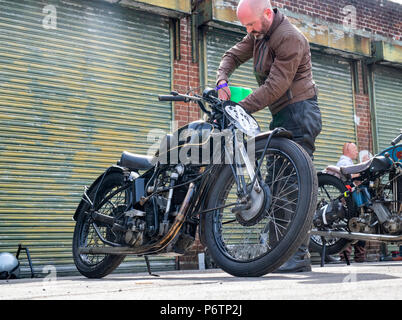 L'uomo il rifornimento di un motociclo Velocette a Bicester Heritage Centre festival volano, Oxfordshire, Inghilterra Foto Stock