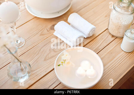 Spa con candele in bagno aromatico e asciugamani laminati su un tavolo di legno. Foto Stock