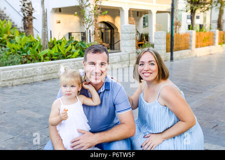 Ritratti di famiglia felice di tre - in stato di gravidanza della madre, padre e figlia divertirsi durante la passeggiata nel parco della città. Family Recreation, spendere tempo per Foto Stock