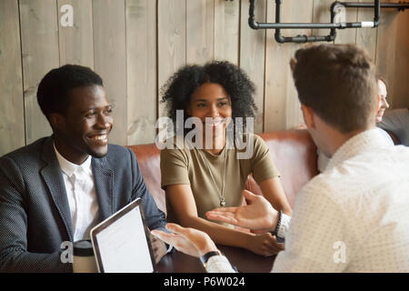 Consulente caucasica a parlare con i clienti di colore nero in coffee shop Foto Stock