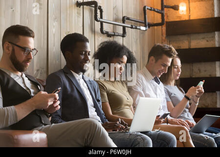 Multirazziale millennial sit di evitare di parlare con i gadget Foto Stock