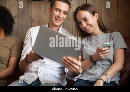 La millenaria amici ridere video divertente seduta in cafe toget Foto Stock