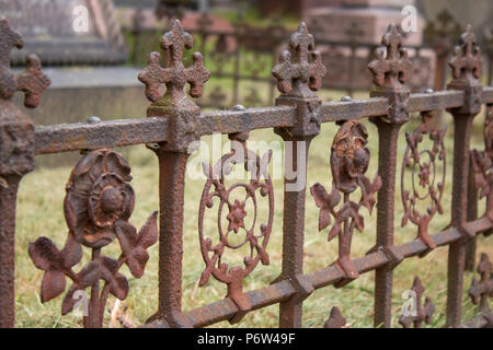 Un arrugginito, decorate, ferro battuto recinto intorno ad un marcatore di tomba nel cimitero di Brompton, Londra Foto Stock