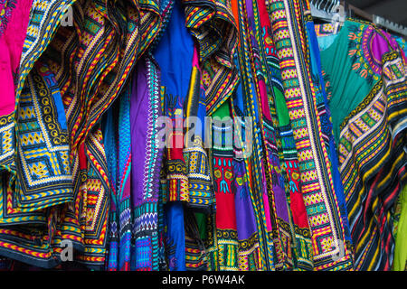 Colorate magliette africana e abiti per la vendita in un mercato di Brixton. Foto Stock