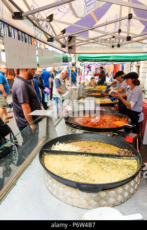 Vista lungo stallo di mercato la vendita di cibo caldo a Le Weekend evento francese, Sandwich, Regno Unito. Diversi grandi cauldrons con il cibo, la gente in attesa di essere serviti. Foto Stock