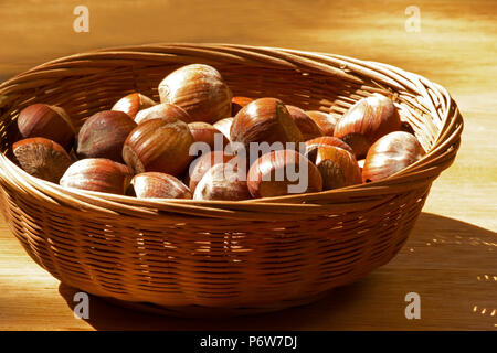 Le nocciole in un cesto su un tavolo di legno Foto Stock