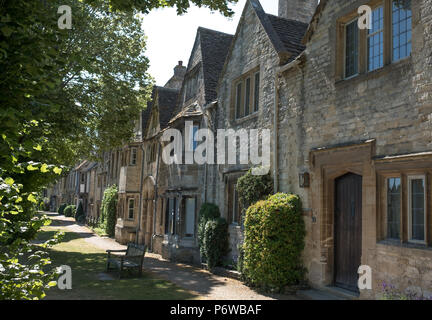 Fila di vecchie case di pietra di fronte ad un orlo di erba in Sheep Street off High Street a Burford, la storica città di mercato nelle Cotswolds REGNO UNITO Foto Stock