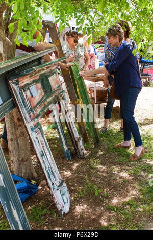 Una donna guarda un antico ruota di carro e vecchio camino mantel pezzi in vendita a Braselton antico Festival il 28 aprile 2018 a Braselton, GA. Foto Stock