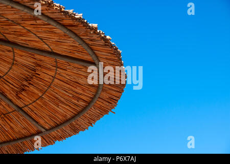 Tetto di Paglia di ombrellone contro il cielo blu. Vacanza topic.summer beach, sfondo per un iscrizione.Texture della bella naturale di paglia ombrelloni realizzato da fieno in un tropical resort nel deserto, Foto Stock