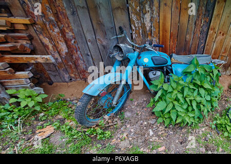 Un vecchio abbandonato cavalletto di motoveicoli nei pressi di un recinto nel villaggio Foto Stock