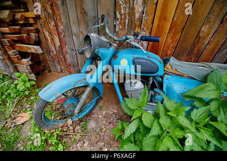 Un vecchio abbandonato cavalletto di motoveicoli nei pressi di un recinto nel villaggio Foto Stock