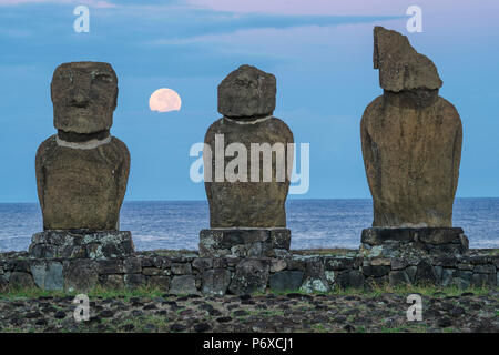 America del Sud, il Cile, l'isola di pasqua, Isla de Pascua, Moai stone figure umane sotto un cielo notturno al sorgere della luna Foto Stock