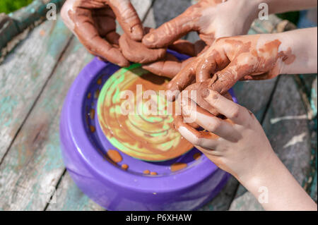 Mamma e figlia sono stampati da argilla su un tornio del vasaio. Le donne e i bambini con le mani in mano. Foto Stock