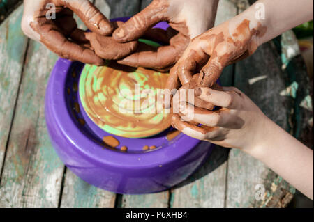 Mamma e figlia sono stampati da argilla su un tornio del vasaio. Le donne e i bambini con le mani in mano. Foto Stock