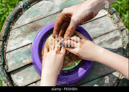 Mamma e figlia sono stampati da argilla su un tornio del vasaio. Le donne e i bambini con le mani in mano. Foto Stock