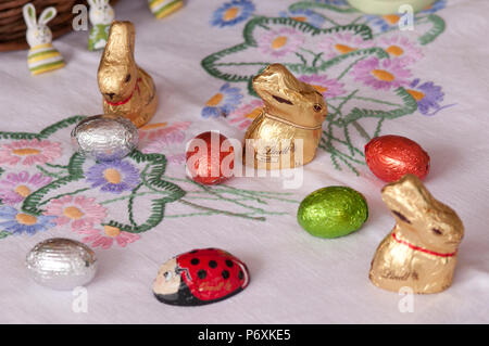 Cioccolatino conigli pasquali e uova su una bella tovaglia Foto Stock