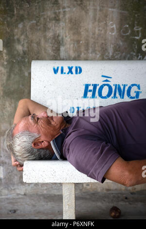 Uomo di dormire su una panca in un Binh , il Vietnam Foto Stock