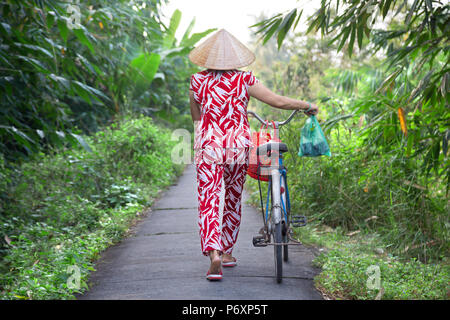 Donna con la bicicletta e cappello conico su un isola di Binh , il Vietnam Foto Stock